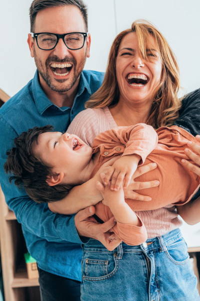 A happy couple holding their laughing child